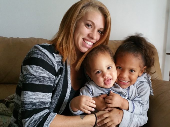 Amanda sitting on a couch with her two young daughters