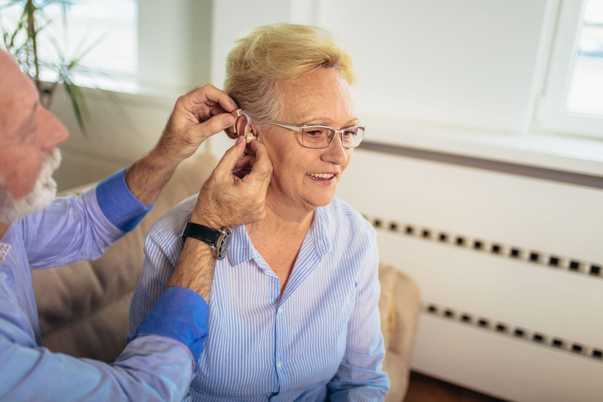doctor fitting a senior woman with a hearing aid