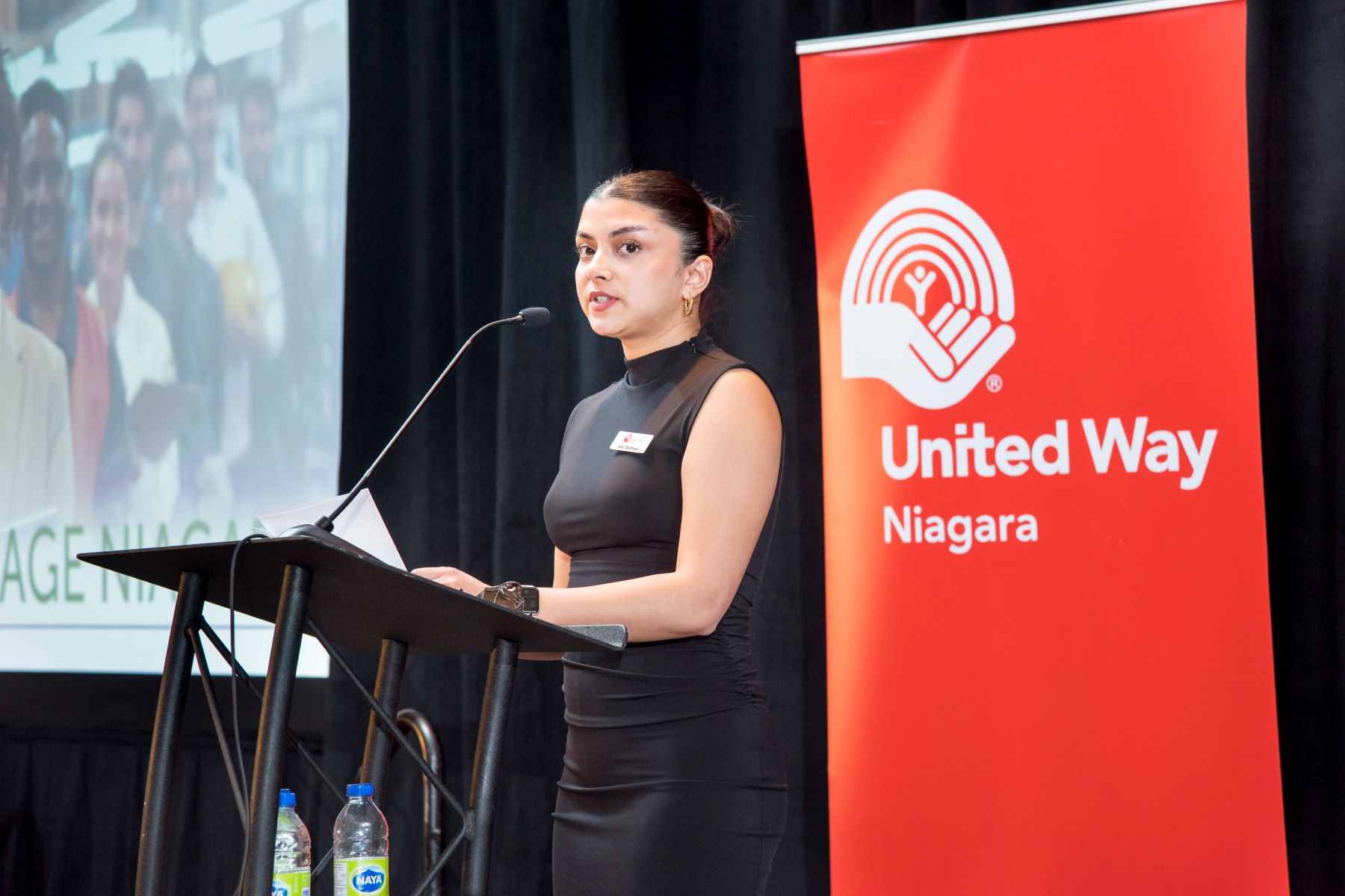 Isha Dadhwal, program coordinator, at the podium, speaking at International Women’s Day event about the benefit and importance of earning a living wage.